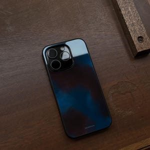May include: A smartphone case with a blue and purple watercolor design. The case has a glossy finish and a black camera module. The brand name "bluestone" is printed at the bottom of the case.