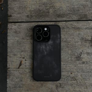 May include: A black smartphone case with a textured, mottled surface finish and a triple-lens camera cutout. The case features a solid black frame and the small, subtle text bluestone printed near the bottom center of the back panel.