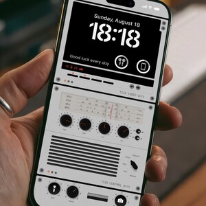 May include: A smartphone mockup with a custom interface showing a digital clock displaying "18:18" and the text "Sunday, August 18". The screen also shows the text "Good luck every day" and the words "TS19 VIDEO Unit" and "TS19 CONTROL Unit". The phone is labeled "MONZA" at the bottom.