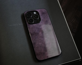 Può includere: Custodia per telefono viola con finitura strutturata e modulo fotocamera nero. La custodia è appoggiata su una superficie grigio scuro, con la frase "we only know" visibile. Design elegante e moderno per smartphone.