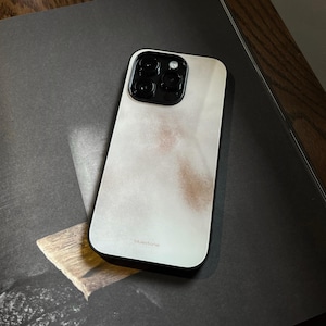 May include: A smartphone case with a black frame and a white and brown abstract design. The case has a glossy finish and a camera cutout with multiple lenses. The word "bluestone" is printed at the bottom.