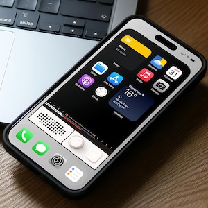 May include: A smartphone with a black case displaying a retro radio interface on the screen. The screen shows app icons, including Notes, App Store, and Calendar. The phone is on a wooden surface near a laptop keyboard and a pair of wireless earbuds.