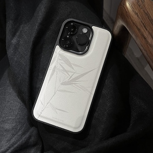 Op de afbeelding: Een smartphonehoesje met een wit achterpaneel met een subtiel, lichtgrijs bamboebladpatroon en een zwart frame. Het cameramodulegedeelte is zwart met drie ronde lenzen en een flitser. Het woord bluestone staat in kleine letters afgedrukt.