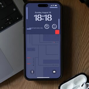 May include: A black smartphone with a dark blue screen displaying the time 18:18, the date Sunday, August 18, and the text "Good luck every day". The screen also shows a map with red lines and the words "FLACHLIONT" and "CAMERA".
