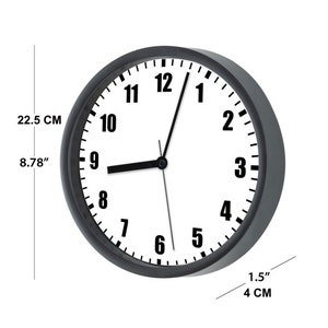K&ouml;nnte beinhalten: Eine schwarz-wei&szlig;e Analoguhr mit schwarzen Zeigern und einem wei&szlig;en Zifferblatt. Die Uhr hat einen Durchmesser von 22,5 cm und ist 4 cm dick.