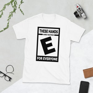 May include: White t-shirt with a black graphic that says "These Hands Are Rated E For Everyone".