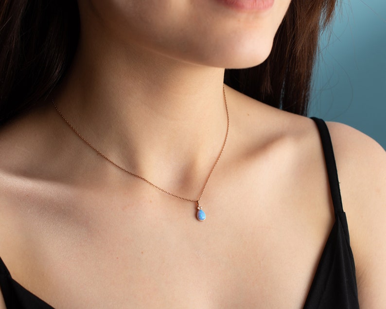 Puede incluir: Un delicado collar de cadena de oro rosa con un colgante de &oacute;palo en forma de l&aacute;grima.