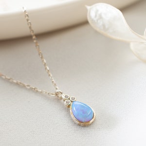 Puede incluir: Un delicado collar de cadena de plata con un colgante de &oacute;palo en forma de l&aacute;grima acentuado con peque&ntilde;as piedras transparentes.