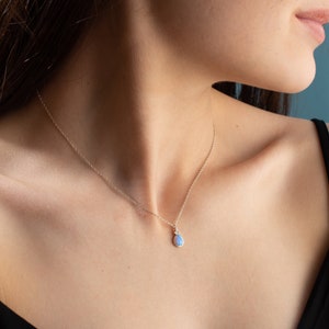 Puede incluir: Un collar de cadena de plata con un colgante en forma de l&aacute;grima con una piedra de &oacute;palo azul claro.