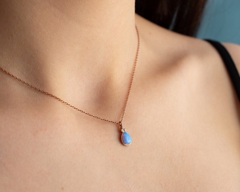 Puede incluir: Un delicado collar de cadena de oro rosa con un colgante en forma de l&aacute;grima que presenta una &oacute;palo azul claro y dos peque&ntilde;os diamantes.