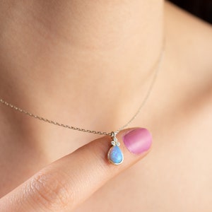 Puede incluir: Un delicado collar de cadena de plata con un colgante de &oacute;palo en forma de l&aacute;grima acentuado con tres peque&ntilde;os diamantes.