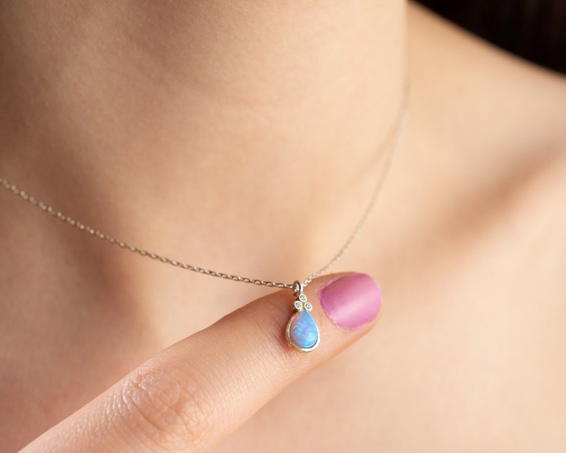 Puede incluir: Un delicado collar de cadena de plata con un colgante de &oacute;palo en forma de l&aacute;grima acentuado con tres peque&ntilde;os diamantes.