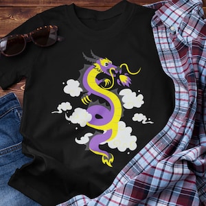 以下が含まれることがあります： 黒地に紫と黄色の龍のグラフィックがプリントされたTシャツ。龍は白い雲に囲まれている。