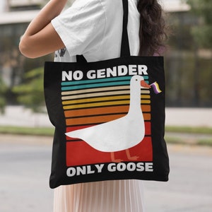 May include: A black tote bag with a white goose graphic and the text "NO GENDER ONLY GOOSE". The goose is holding a pride flag.
