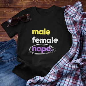 Peut inclure: T-shirt noir avec le texte "male female nope." en blanc, jaune et violet.