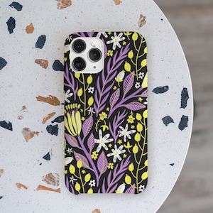 May include: A black phone case with a floral pattern featuring purple leaves, yellow flowers, and white flowers.