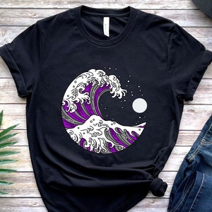 May include: Black t-shirt with a graphic of a purple and white wave with a moon in the background. The wave is in a circle.