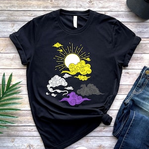 May include: Black t-shirt with a yellow, white, and purple sun and clouds graphic. The graphic is a stylized representation of the non-binary pride flag.