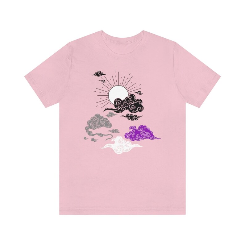 以下が含まれることがあります： 黒、白、グレー、紫の太陽と雲のグラフィックが描かれたピンクのTシャツです。