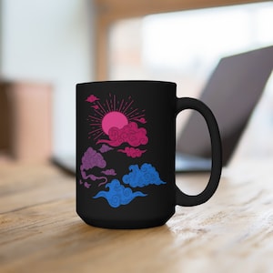May include: A black ceramic mug with a bi-pride flag inspired design. The design features a pink and blue sun with clouds in the sky.