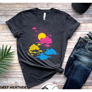 May include: A dark grey heather t-shirt with a graphic of a sun and clouds in pink, yellow, and blue colors. The graphic is a representation of the pansexual pride flag.