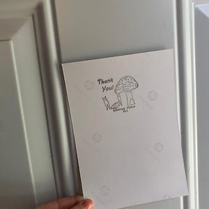 K&ouml;nnte beinhalten: Eine Dankeskarte mit einer handgezeichneten Illustration eines Pilzes und dem Text "Danke!" und "Whitney Yadon Art".