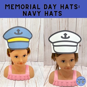 May include: Two paper hats for kids to wear for Memorial Day. The hats are navy blue and white and have an anchor on the front. The hats are on a wooden background.