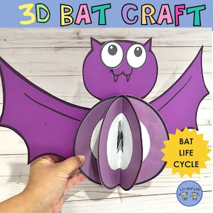 Puede incluir: Una manualidad de murciélago 3D de color morado con ojos grandes y una boca sonriente. El murciélago tiene alas que se despliegan y un círculo blanco en el centro del cuerpo. El texto "BAT LIFE CYCLE" está escrito en una estrella amarilla.