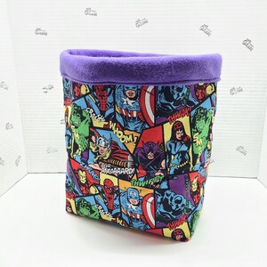 May include: A purple fabric storage bin with a comic book print featuring Marvel superheroes like Captain America, Iron Man, Hulk, Thor, and Black Widow. The print includes speech bubbles with phrases like "Crash", "Whom!" and "Asgaaard!"