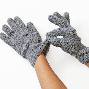 May include: A pair of gray exfoliating gloves made of soft, textured fabric. The gloves are designed for use in the shower or bath to help remove dead skin cells and improve circulation.