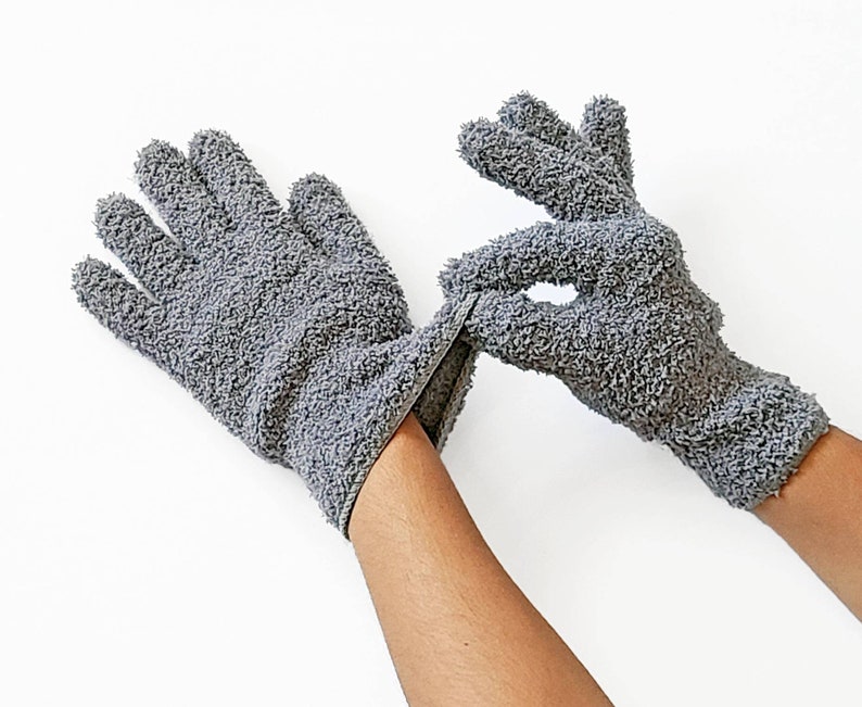 May include: A pair of gray exfoliating gloves made of soft, textured fabric. The gloves are designed for use in the shower or bath to help remove dead skin cells and improve circulation.
