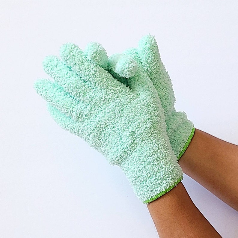 May include: A pair of light green exfoliating gloves with a lime green trim. The gloves are made of a soft, textured fabric.