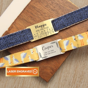 May include: Two personalized pet ID tags with engraved text. One tag is on a blue woven strap and the other on a yellow strap with a bird pattern. The tags display names and contact information. The words "Laser Engraved" are also visible.