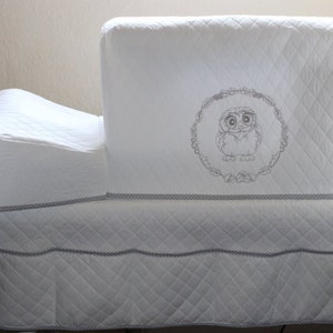 May include: White quilted sewing machine cover with a gray embroidered owl design. The cover has a built-in storage pocket.