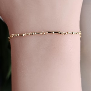 May include: A delicate gold chain bracelet with small, round beads and twisted links.