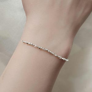 May include: A silver chain bracelet with small round beads.