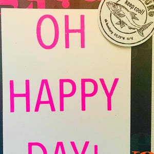 K&ouml;nnte beinhalten: Ein Mixed-Media-Kunstwerk mit den Worten "OH HAPPY DAY!" in leuchtendem Pink, vor einem Hintergrund mit dem Wort "GOOD" in Pink. Ein runder Aufkleber mit einer Fischillustration und dem Text "HAMBURG keep cool!" ist ebenfalls vorhanden.