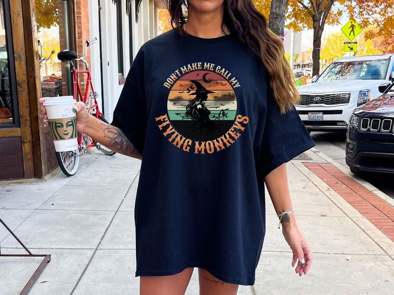 May include: A black t-shirt with a vintage-style graphic of a witch with the text "Don't Make Me Call My Flying Monkeys".