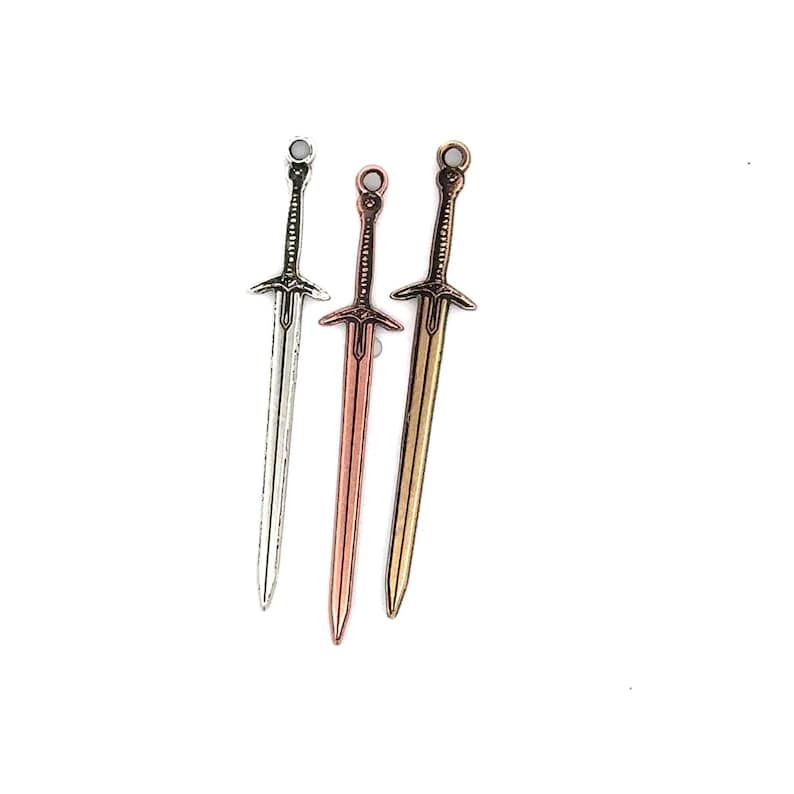 May include: Three miniature swords in different metal finishes: silver, copper, and gold. The swords have intricate details and are perfect for crafting or jewelry making.