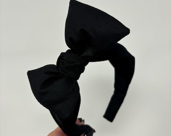 May include: A black fabric headband with a large, knotted bow.