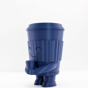 May include: A blue ceramic figurine of a smiling coffee cup holding another coffee cup. The figurine has a textured surface and a happy face.