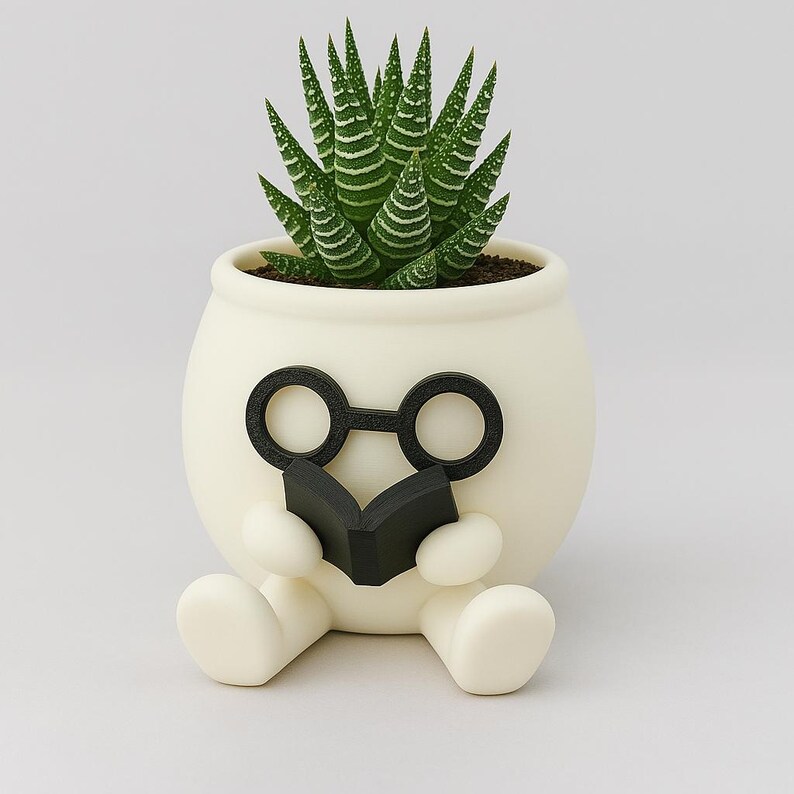 May include: White ceramic planter shaped like a person wearing glasses and holding a book, with a green succulent plant inside.