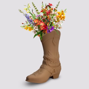 May include: A brown cowboy boot vase filled with a bouquet of colorful flowers, including purple, pink, yellow, and orange blooms.