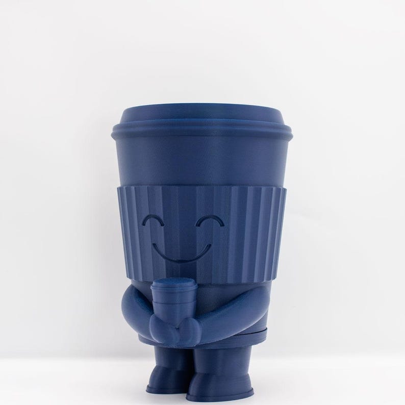 May include: A blue ceramic figurine of a coffee cup with a smiling face, holding a smaller coffee cup in its hands.