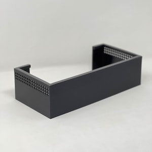 Puede incluir: Una caja rectangular negra abierta con un panel lateral perforado. La caja está hecha de un material resistente y tiene un diseño elegante y moderno.