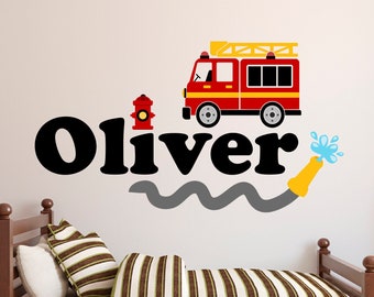May include: A red fire truck with a yellow ladder and a black hose is spraying water. The words "Oliver" are in black letters with a gray wavy line underneath. A red fire hydrant is to the left of the name.