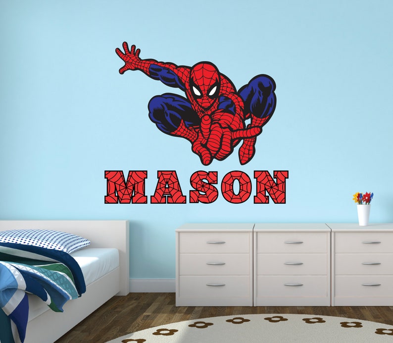 Puede incluir: Un adhesivo de pared de Spiderman rojo y azul con un dise&ntilde;o de telara&ntilde;a. El nombre "MASON" est&aacute; escrito en rojo con un dise&ntilde;o de telara&ntilde;a.