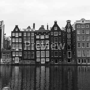 May include: Black and white photo of a row of traditional Dutch canal houses with a reflection in the water.