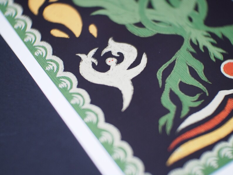 May include: Close-up of a decorative art print with a black background. The print features white, green, yellow, and orange stylized shapes. A white figure with red dots is in the center, surrounded by green foliage.