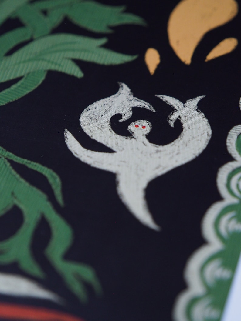 May include: Close-up of a black textile with a white, stylized figure with red eyes. Green leaves and yellow shapes are in the background. The figure has a unique, abstract design.